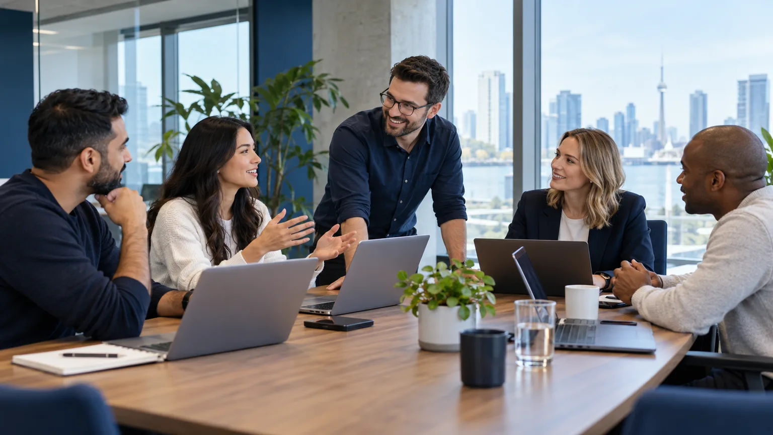 Illustrative scene: a diverse Canadian small-business leadership team discussing technology around a conference table, laptops and unobtrusive network equipment, bright contemporary workplace.